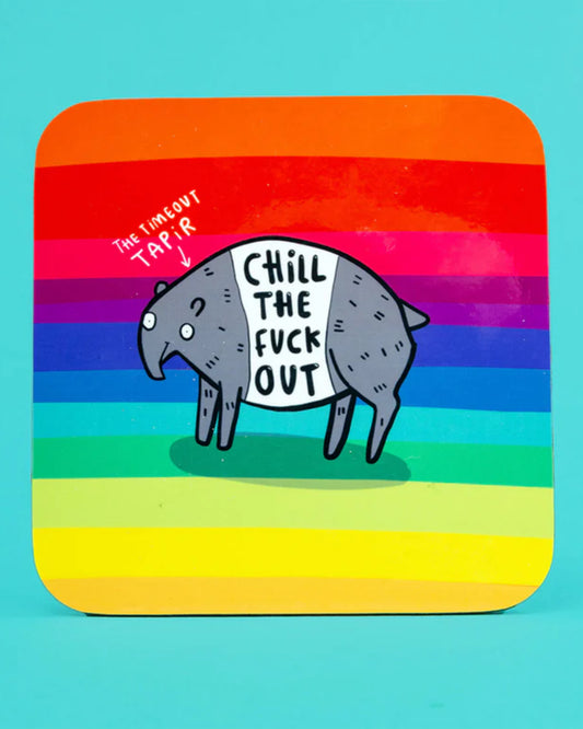 The Katie Abey “Chill The Fuck Out” coaster on a bright yellow surface beside a mug and biscuits. The rainbow striped design with a funny illustrated tapir makes this Rebel Romance homeware piece a playful and uplifting gift.