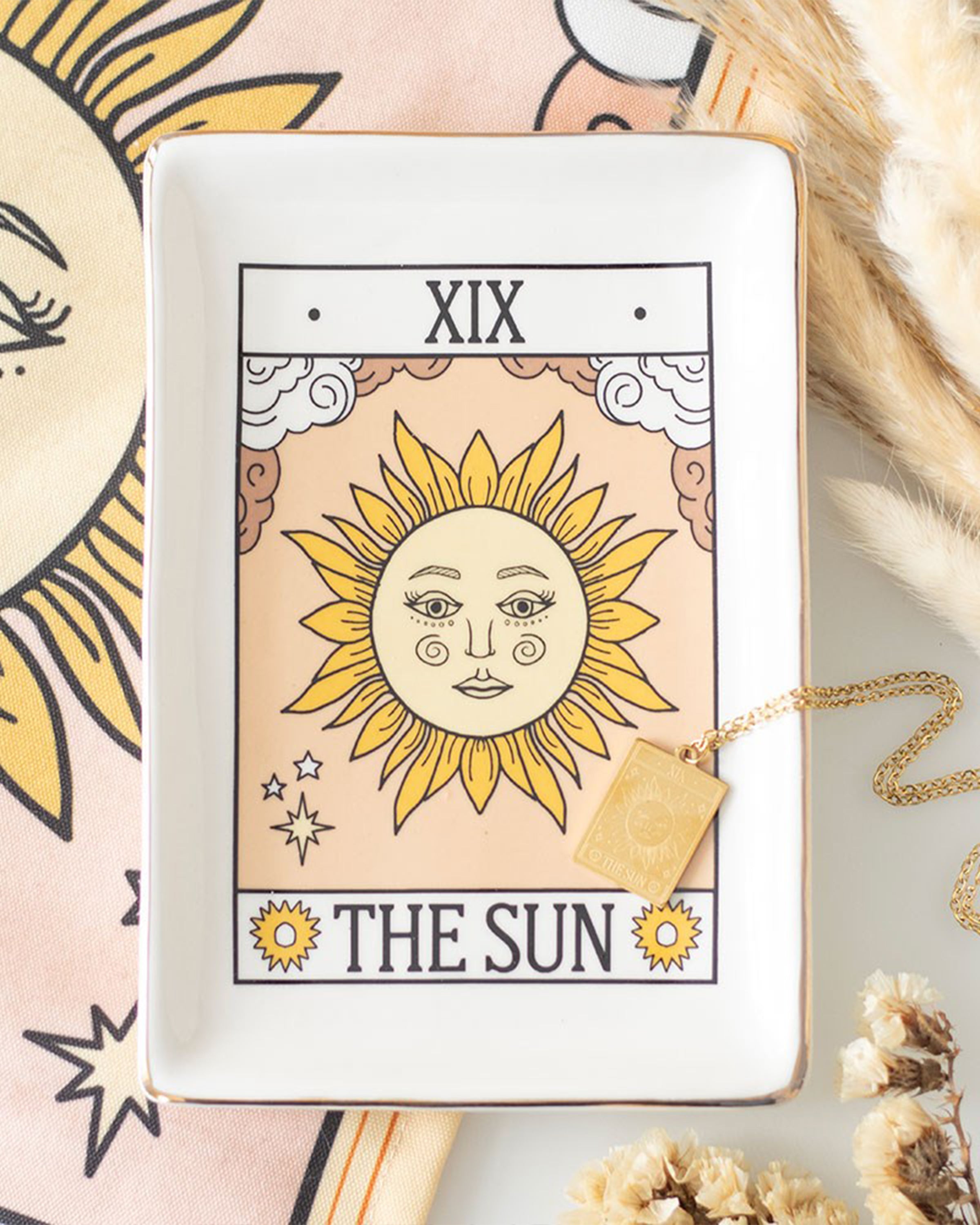 Flatlay of The Sun tarot trinket dish by Rebel Romance styled with gold jewellery and dried flowers. A mystical ceramic dish with gold edging, perfect for holding keys, rings and magical little treasures.