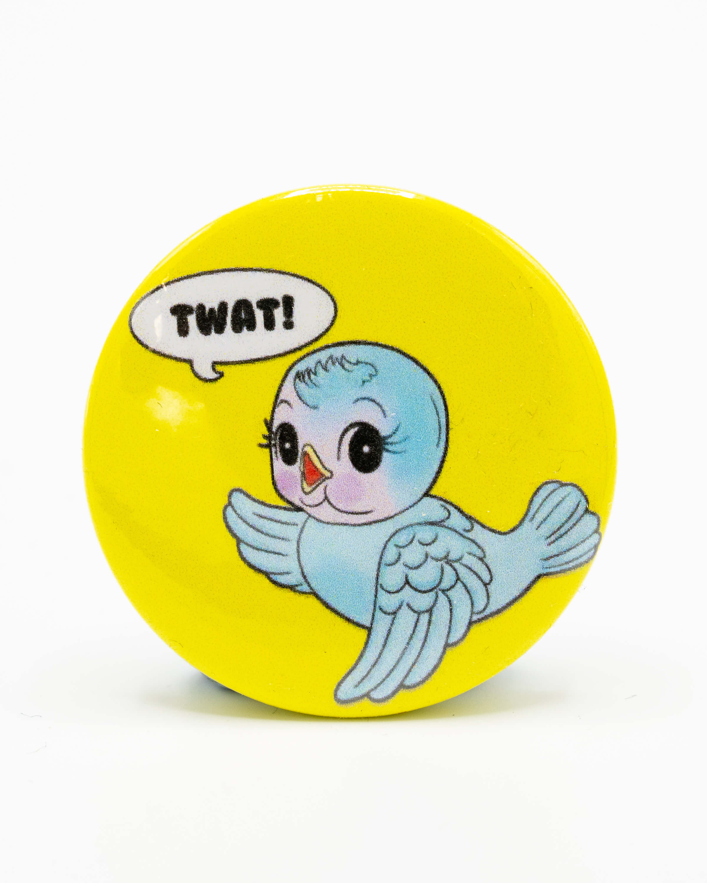 Round yellow button badge with a cartoon kitsch blue bird and speech bubble saying 'TWAT!' . A retro inspired design from Bite Your Granny.
