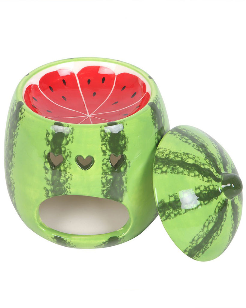 A front view of the watermelon-shaped oil burner with its lid removed, showing the deep red interior with black seed details. The heart-shaped cutouts create a playful aesthetic while allowing light from the tealight to shine through.