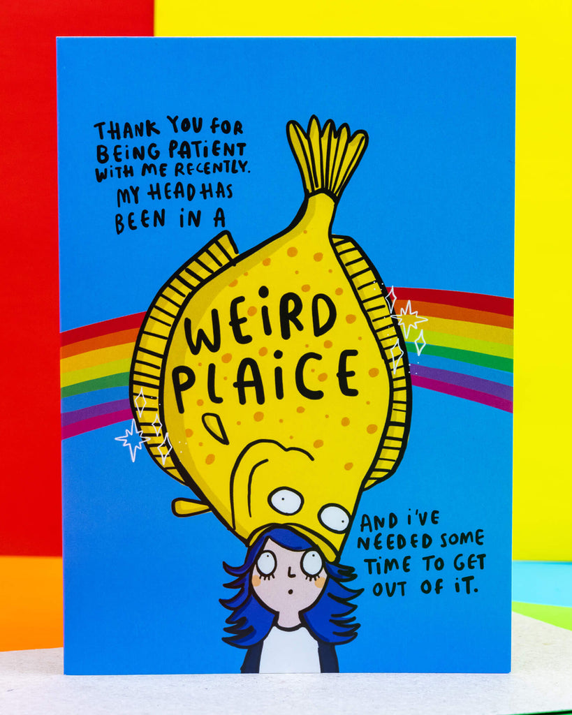 Bright and colourful A6 greeting card from Rebel Romance featuring a cartoon of a yellow fish (plaice) sitting on a character's head with rainbow stripes behind. The text reads: “Thank you for being patient with me recently. My head has been in a weird plaice and I’ve needed some time to get out of it.” Designed by Katie Abey, this mental health card is perfect for expressing gratitude and reconnecting after a rough patch.