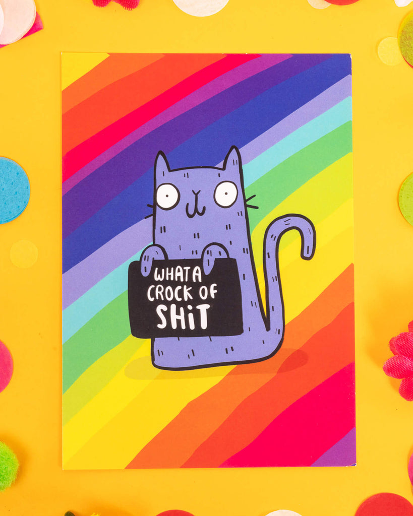 A colourful A6 postcard featuring a purple cartoon cat holding a sign that says “What a Crock of Shit” on a bold rainbow background. Designed by Katie Abey, this cheeky sweary card is perfect for millennials who love alternative humour, quirky stationery, and unapologetically honest gifts.