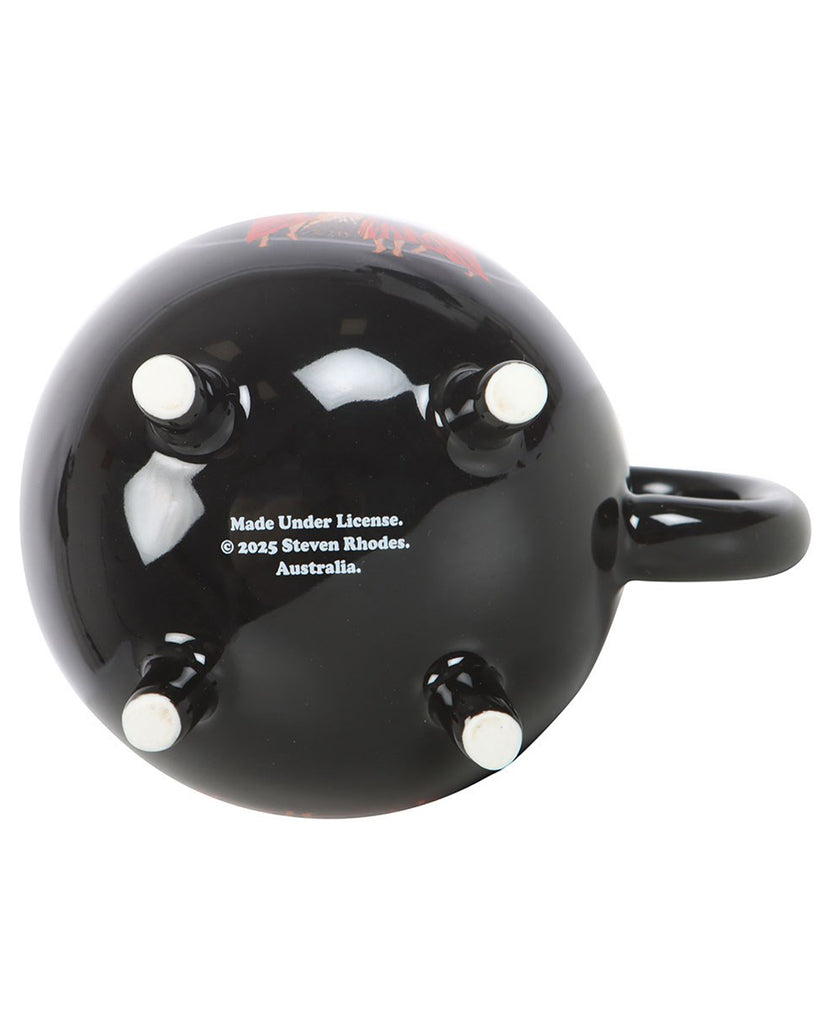 Bottom view of the Rebel Romance Witches' Brew Cauldron Mug by Steven Rhodes, showing its four sturdy feet and licensing details. The black ceramic mug is shaped like a cauldron, perfect for gothic and alternative homeware lovers.