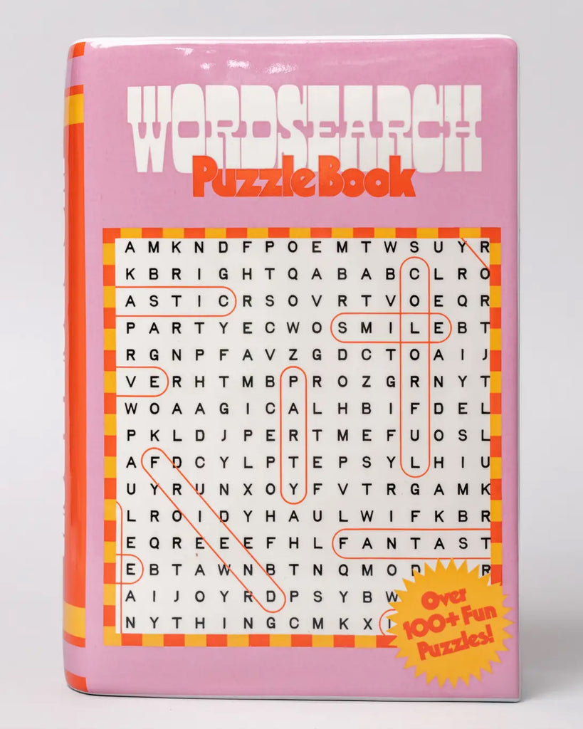 Close-up of the ceramic vase styled as a word search puzzle book, with uplifting words like “SMILE” and “PARTY” highlighted on the front cover, from Rebel Romance.