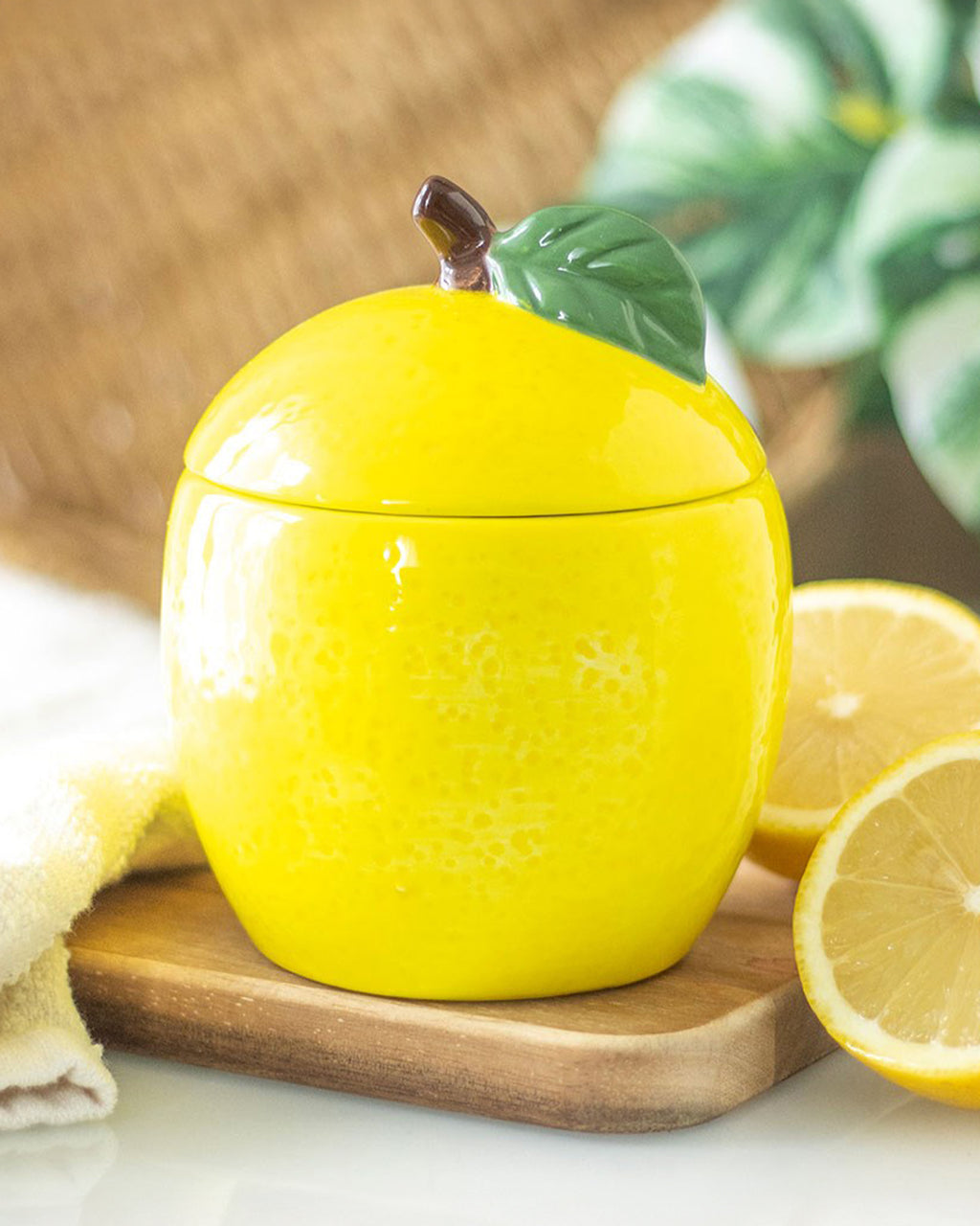 The lemon candle jar styled on a wooden surface, surrounded by fresh lemon slices. Its vibrant citrus design makes it a bright and cheerful addition to any room.