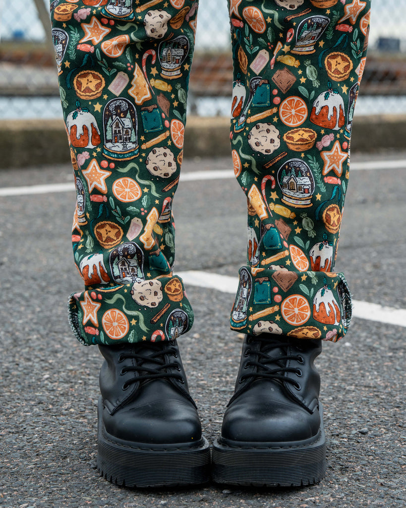 Close-up of the roll ups on the Rebel Romance Yuletide Treats Dungarees worn by Erin Porter. The fabric shows a bold festive pattern with cookies, oranges, puddings and Christmas trees.